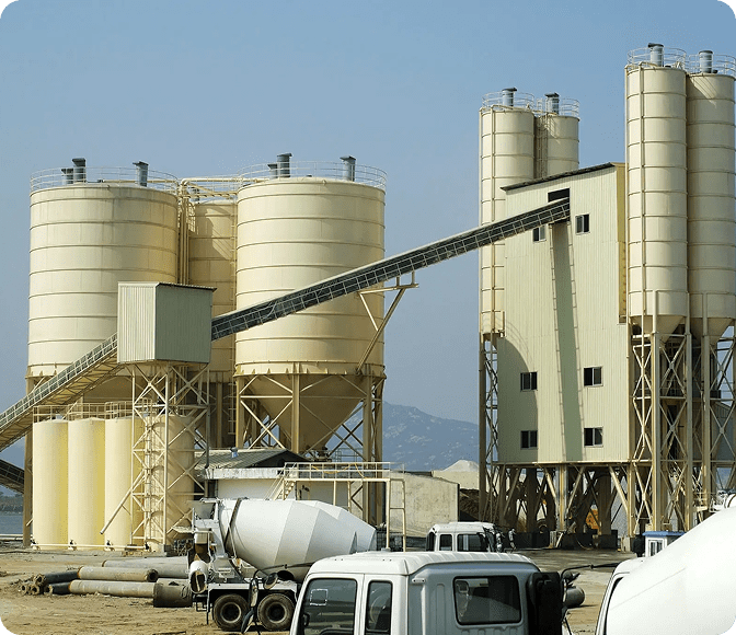 Industrial cement plant with silos and trucks.